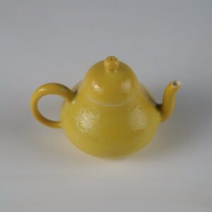 45-degree high angle view of bright yellow pear teapot showing intricate Pa Hua hundred flowers pattern