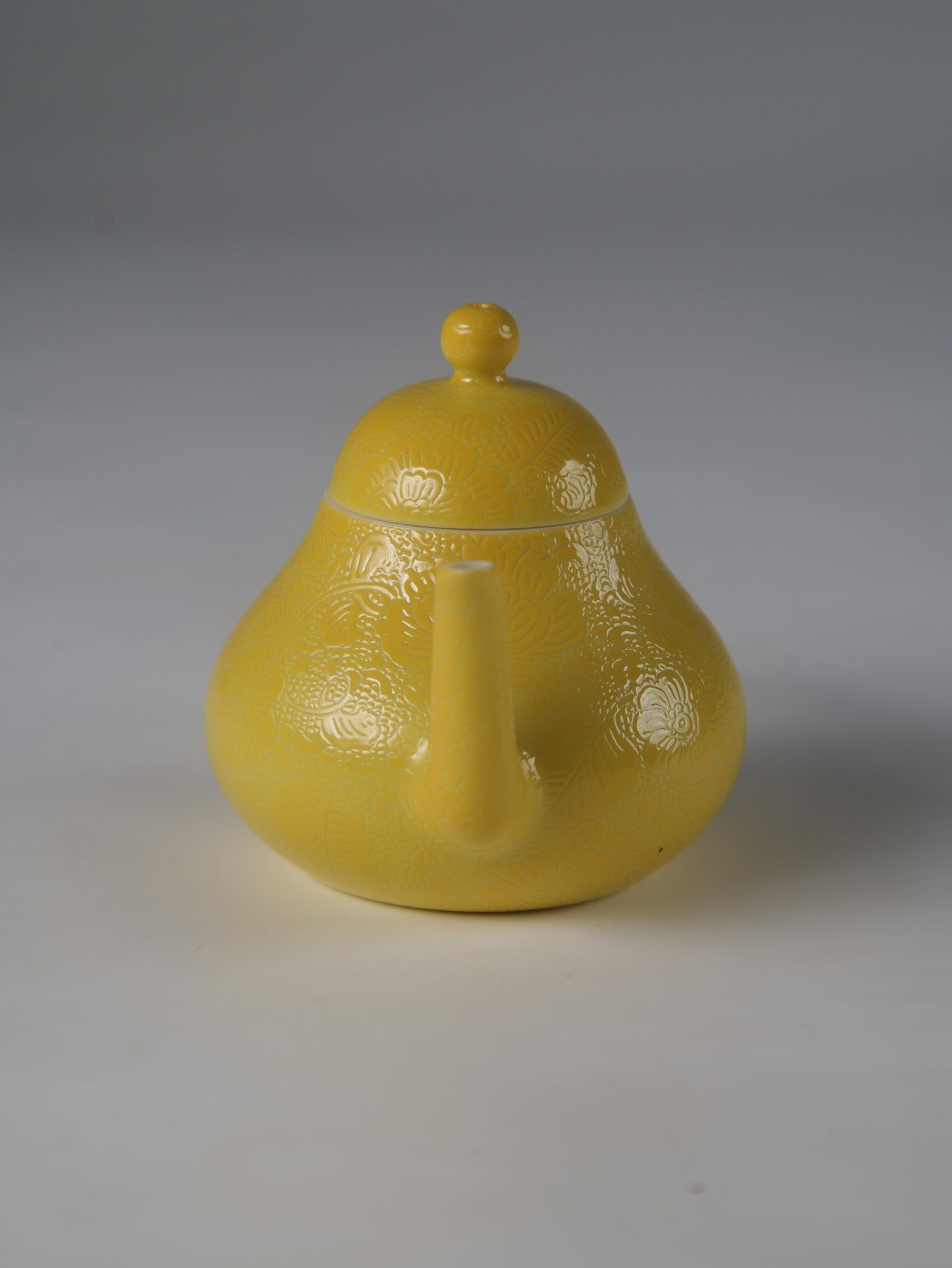 Bright Yellow Pear Teapot – Front Spout View Eye-level front view facing the spout of a bright yellow pear-shaped porcelain teapot on white background