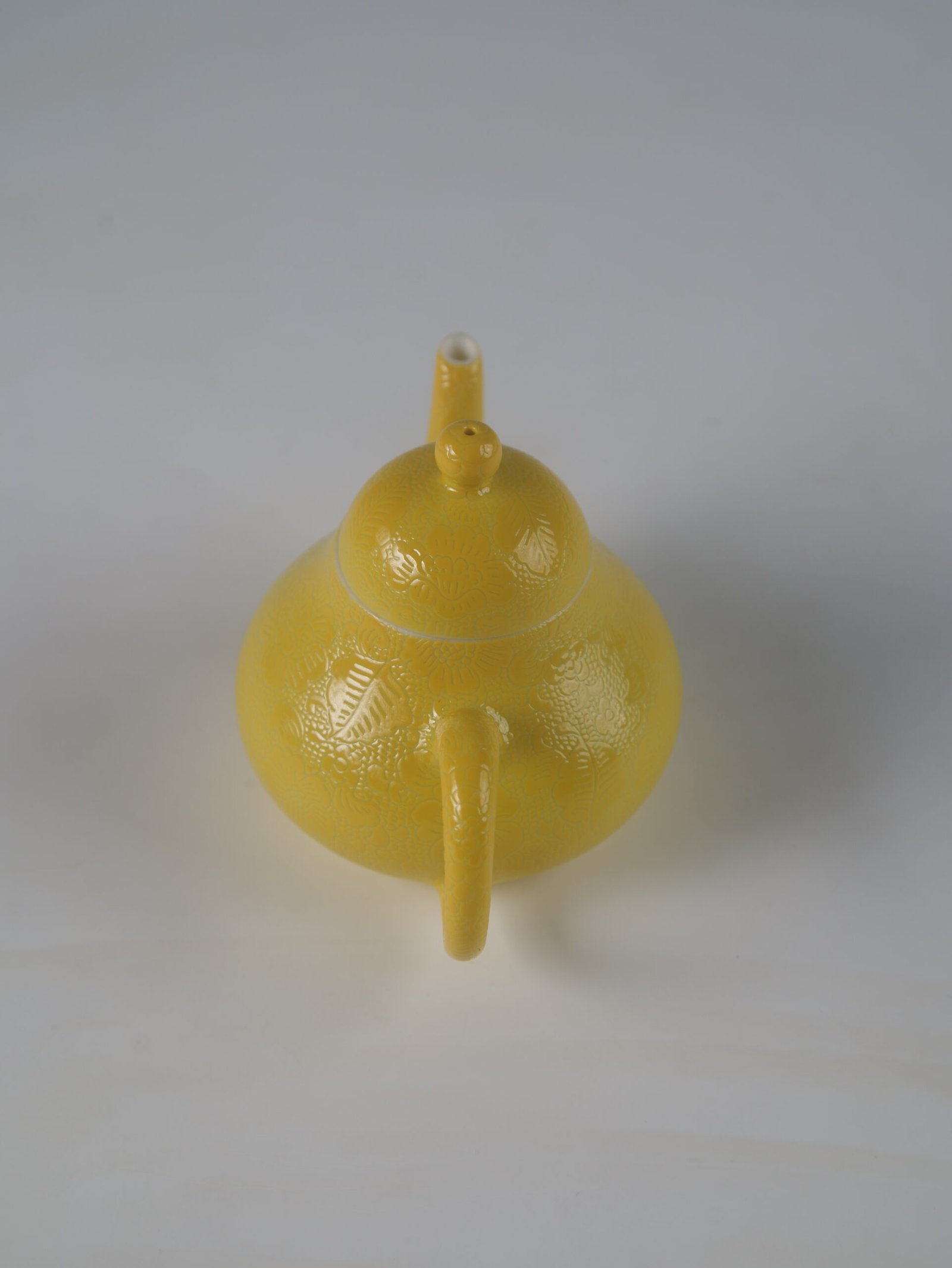 Bright Yellow Pear Teapot – High Angle Handle Perspective High angle rear perspective view showing the handle and lid knob of a bright yellow pear teapot