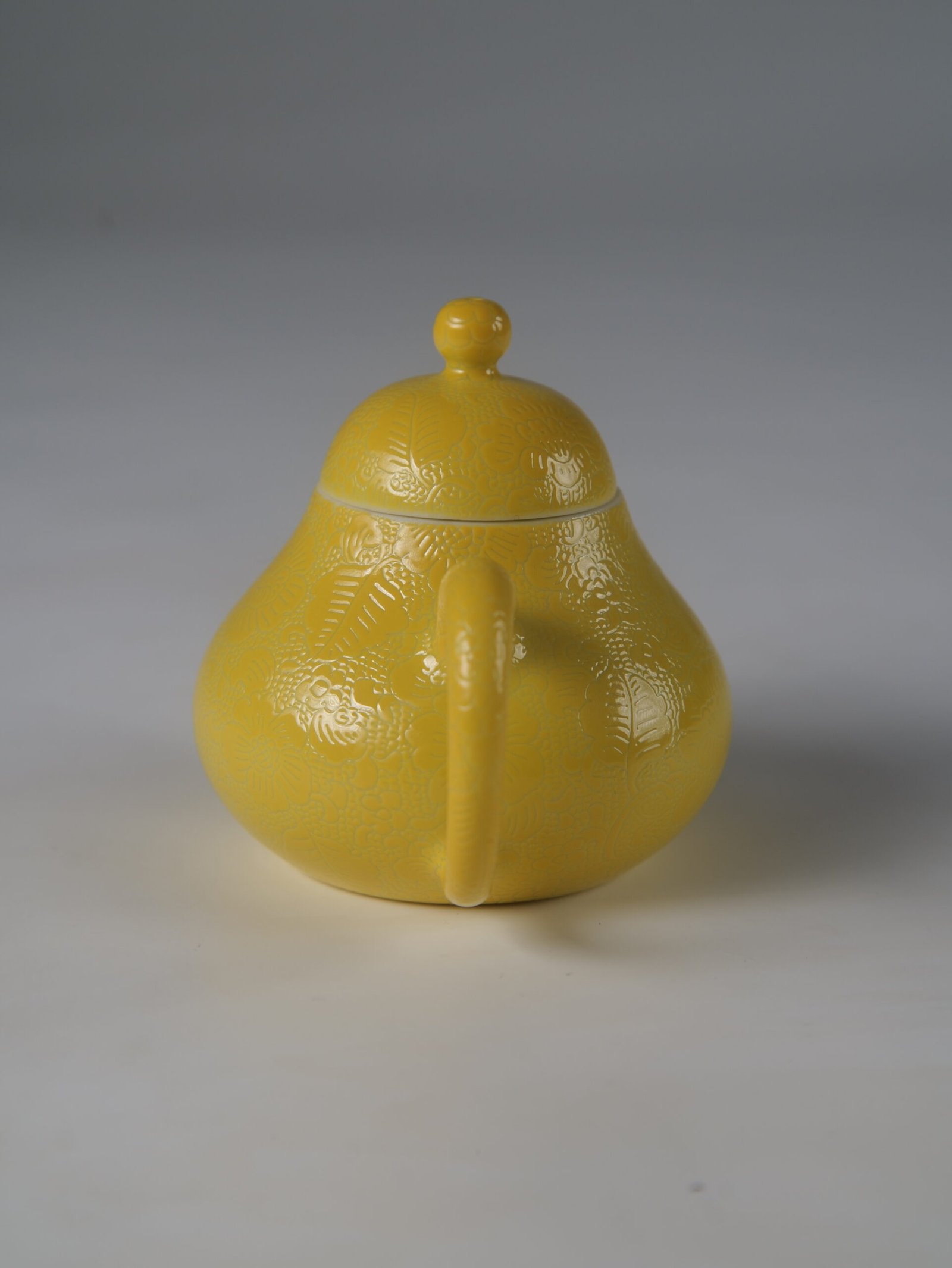Bright Yellow Pear Teapot – Rear Handle View Eye-level rear view facing the handle of a bright yellow pear-shaped porcelain teapot