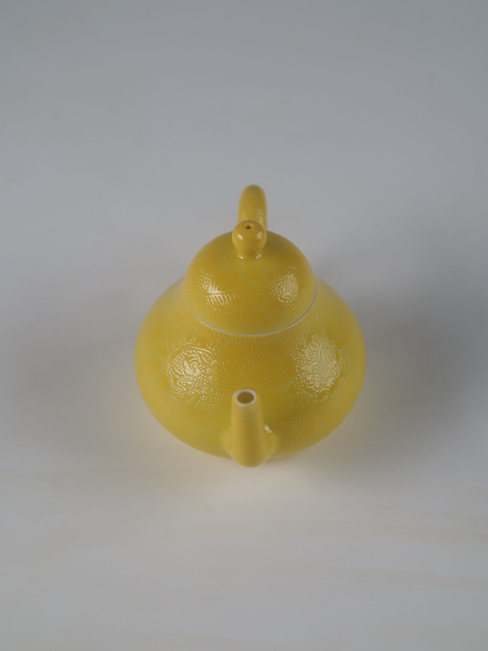 Bright Yellow Pear Teapot – High Angle Spout Perspective High angle front perspective view facing the spout of a bright yellow pear-shaped porcelain teapot