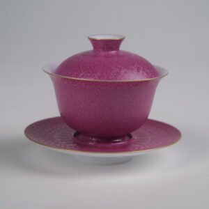 Side view of the Carmine Red Elegant Charm Gaiwan full set featuring vibrant rose-red rouge glaze, gold rim accents, and intricate engraved Swastika Pa Hua pattern