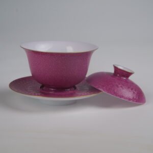 Side view of the Carmine Red Elegant Charm Gaiwan with its lid removed and resting beside the saucer, showing the white porcelain interior, vibrant rose-red rouge glaze, gold rim accents, and intricate Swastika Pa Hua pattern