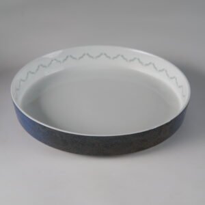 Angled top view of porcelain plate showing carved exterior pattern and white interior