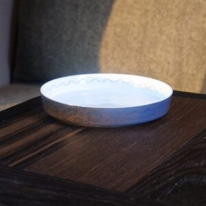 Carved porcelain plate with blue flower pattern placed on dark wooden table