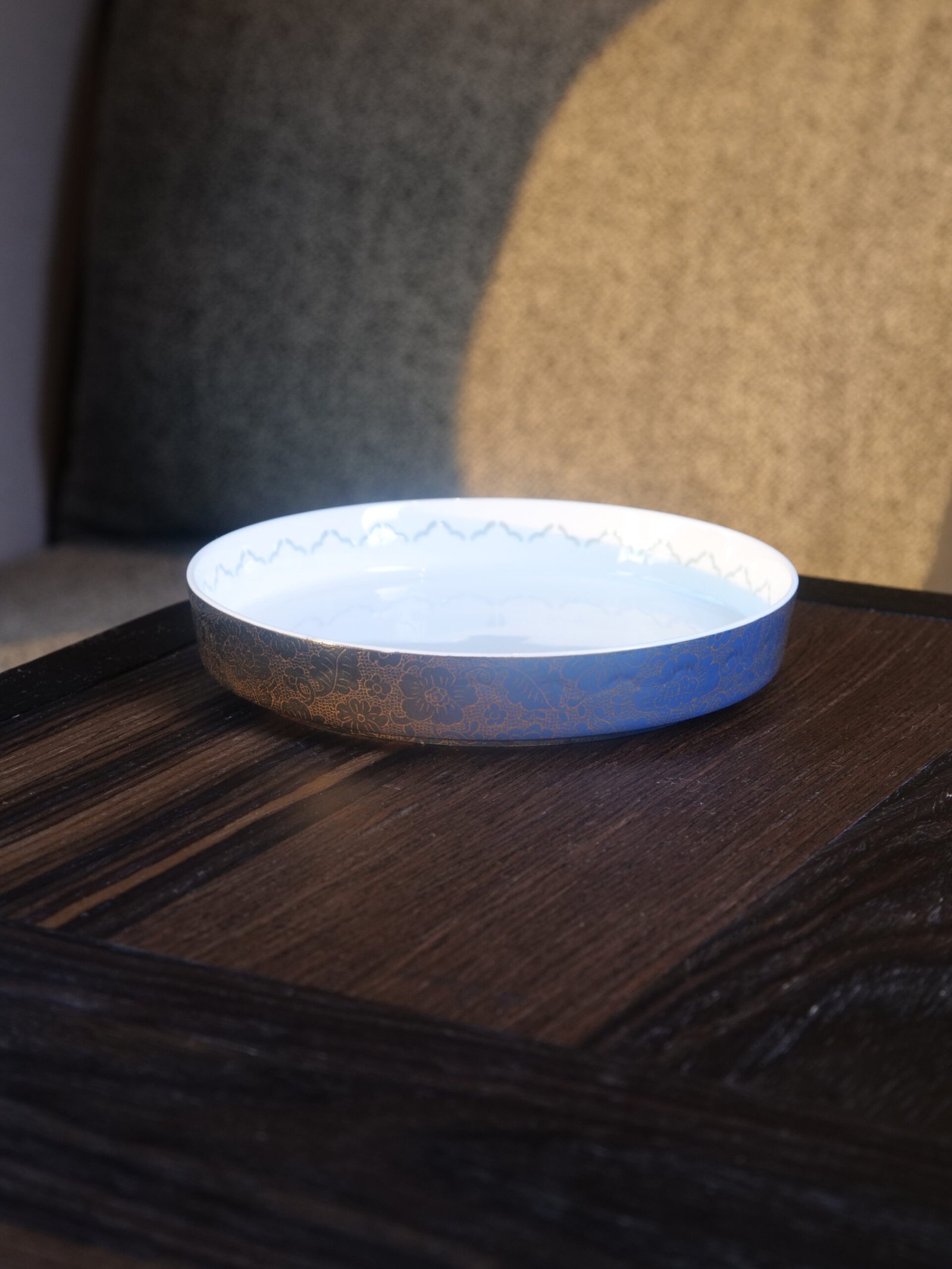 Carved Linglong Porcelain Plate - Lifestyle View Carved porcelain plate with blue flower pattern placed on dark wooden table
