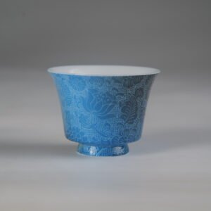 Front view of the East Breaking Dawn deep blue porcelain horseshoe cup featuring intricate traditional floral carving patterns