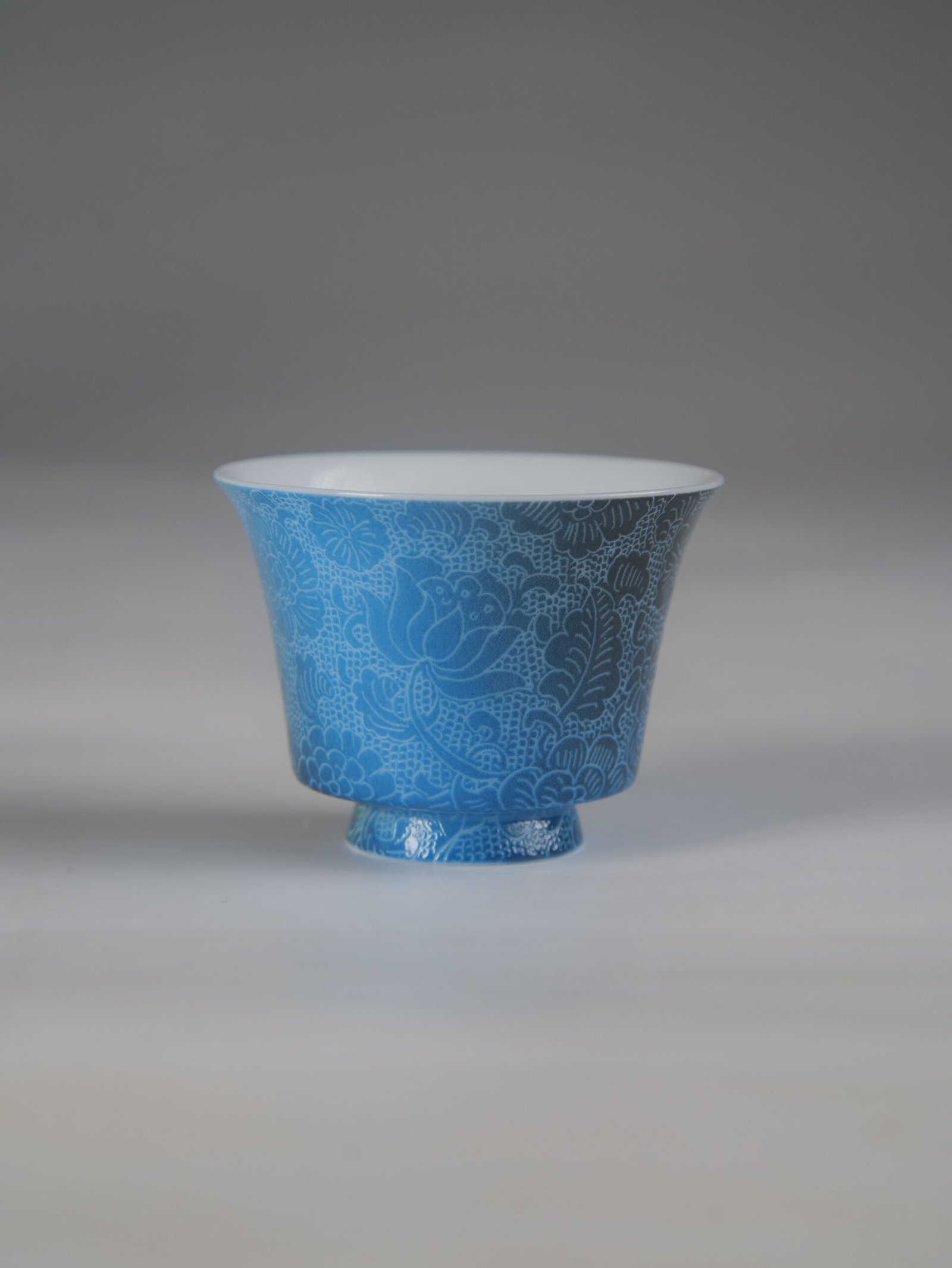 east-breaking-dawn-deep-blue-horseshoe-porcelain-cup-front-view Front view of the East Breaking Dawn deep blue porcelain horseshoe cup featuring intricate traditional floral carving patterns