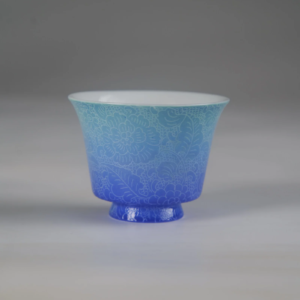 Front view of the East Breaking Dawn gradient blue porcelain horseshoe cup highlighting its vibrant color transition and full-body intricate floral engraved pattern