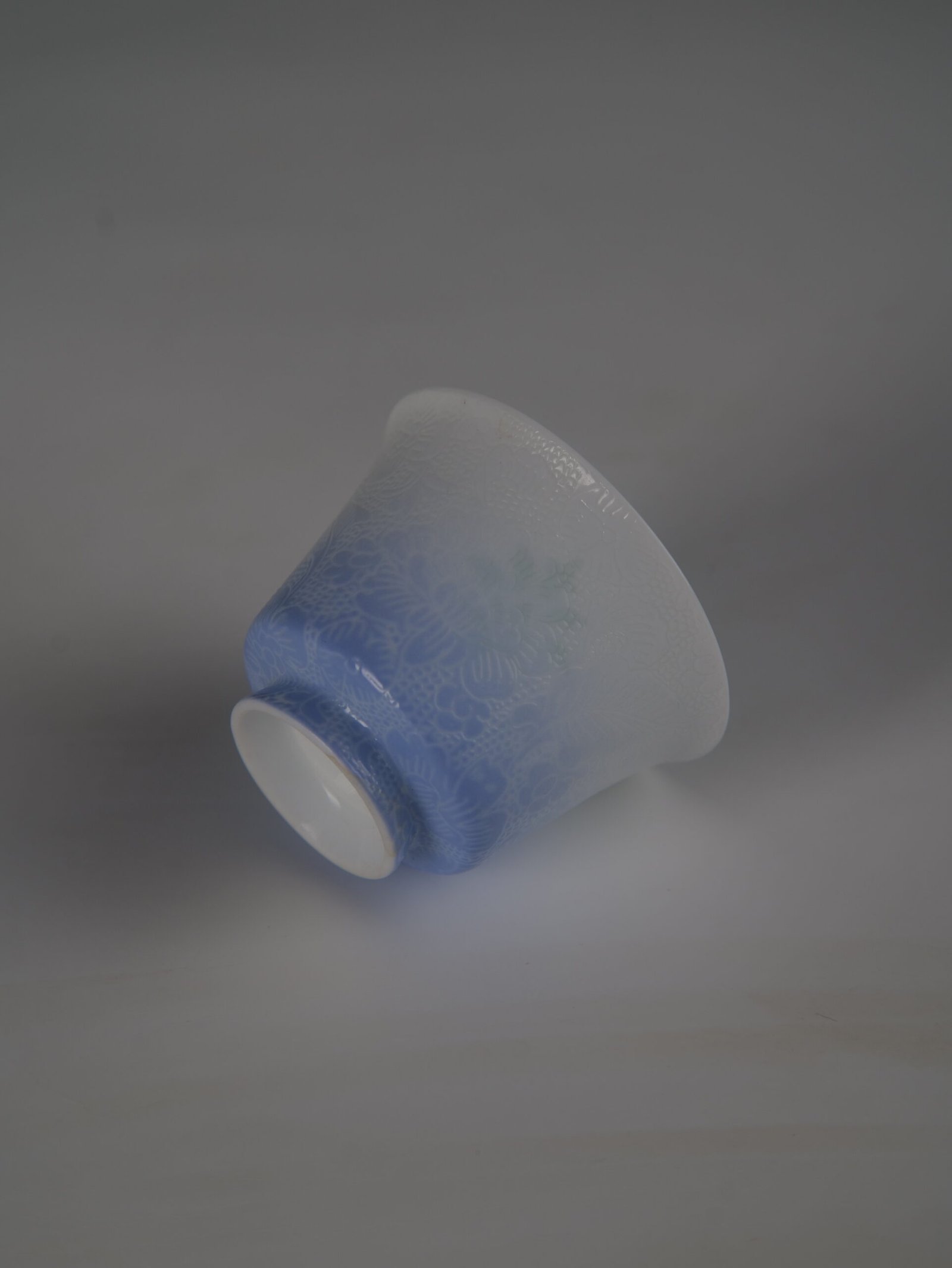 east-breaking-dawn-gradient-blue-horseshoe-porcelain-cup-inverted-detail An inverted view of the East Breaking Dawn gradient blue porcelain horseshoe cup showing its refined base and intricate embossed textures
