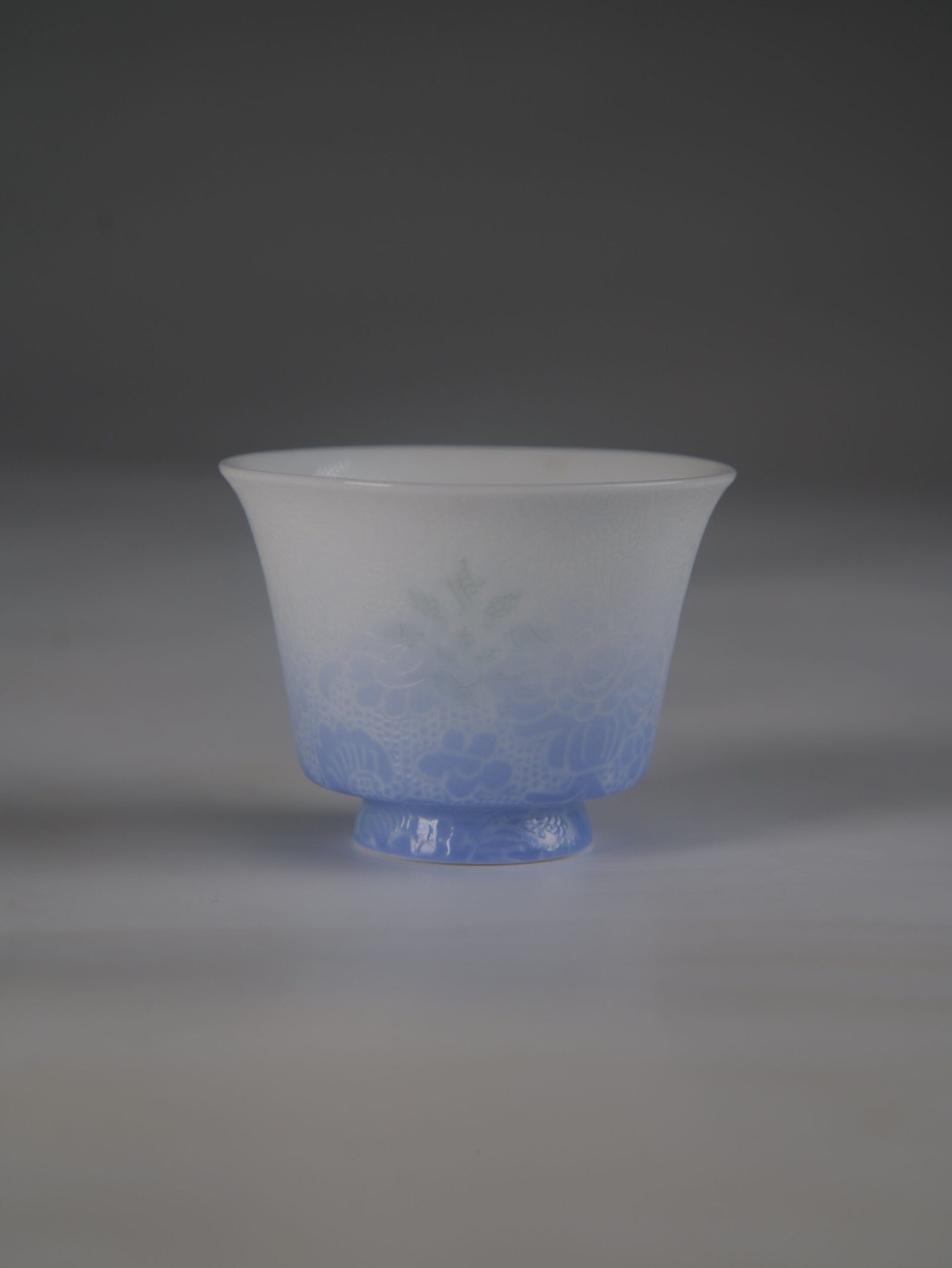 east-breaking-dawn-gradient-blue-horseshoe-porcelain-cup-main Front view of the East Breaking Dawn gradient blue horseshoe porcelain cup with fine embossed guilloche patterns