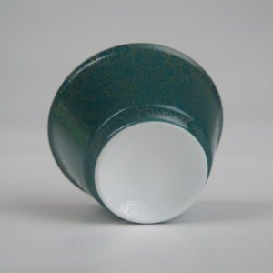 Centered bottom view of the Gold base with blue overlay Linked-loop porcelain cup highlighting the smooth circular white base and gold-infused carved floral textures