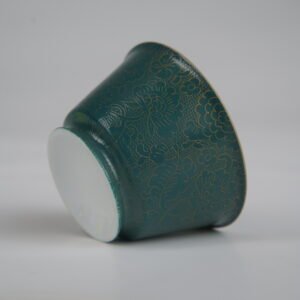 Tilted base perspective of the Gold base with blue overlay Linked-loop porcelain cup highlighting its smooth foot rim and gold-infused carved floral textures