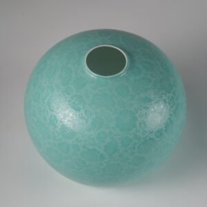 Close up view of intricate carved floral pattern on turquoise green lampshade