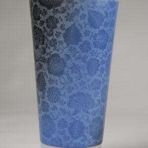 Lying blue ceramic travel cup showing frosted base and carved pattern