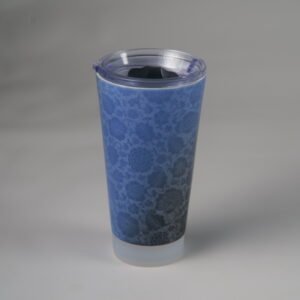 Blue carved ceramic travel cup with clear plastic lid on white background