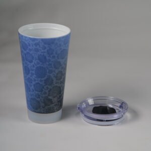 Blue carved ceramic travel cup with lid placed next to it