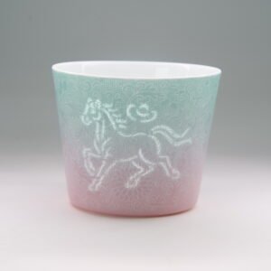 Eye level front view of gradient porcelain cup displaying translucent pierced horse pattern
