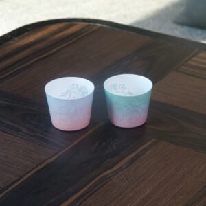 Pair of gradient Jingdezhen linglong porcelain tea cups placed on a wooden tea table