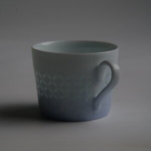 Dark mood side view of light blue gradient coffee cup with handle