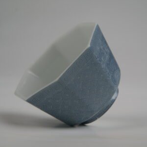 Angled interior and side view of the Lunar Gray Octagonal porcelain cup showcasing its geometric octagonal rim, white interior, and solid lunar gray exterior with intricate engraved lattice patterns