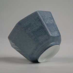 Bottom-angle view of the Lunar Gray Octagonal porcelain cup showcasing its white base, geometric octagonal structure, solid lunar gray glaze, and fine engraved Shang Dynasty Taotie and lattice patterns
