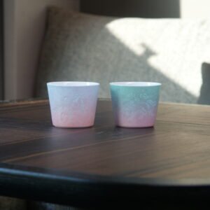 Pair of pastel gradient Jingdezhen porcelain coffee cups placed on a wooden table
