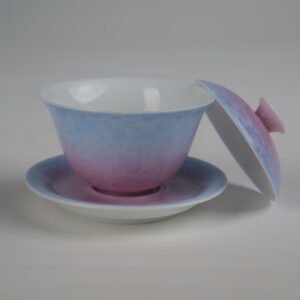 Side view of the Midsummer Dream Gradient Elegant Charm Gaiwan with its lid removed and resting beside the saucer, showing the white porcelain interior, the soft gradient blend of pale purple and pink glaze, and the handcrafted Pa Hua floral pattern