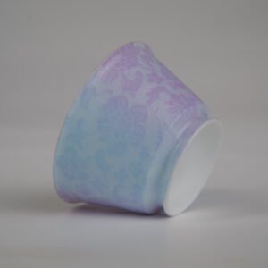 An inverted view of the Misty Lavender Haze Linked-loop porcelain cup highlighting its white foot rim and delicate pastel purple and blue carved floral pattern