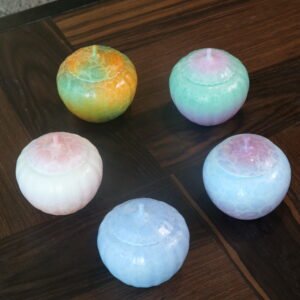 Top-down view of five colorful gradient porcelain melon jars arranged on a wooden tea table
