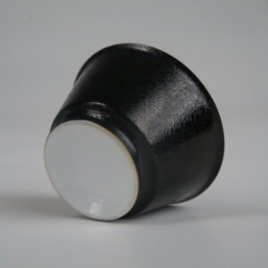 Bottom-up view of the Obsidian Black Linked-loop porcelain cup showcasing its white circular base and detailed dark carved enamel dragon scale pattern