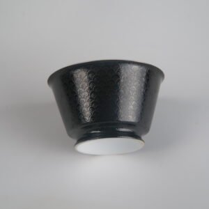 Low-angle view of the Obsidian Black Linked-loop porcelain cup highlighting its white foot base and detailed dark carved enamel dragon scale texture