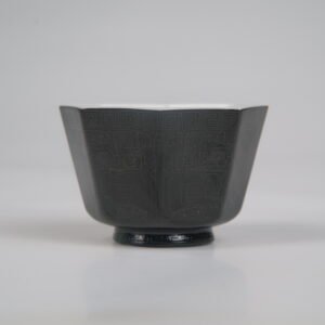 Front view of the Obsidian Black Octagonal porcelain cup displaying its geometric shape, deep obsidian black glaze, and intricate Shang Dynasty Taotie motif with fine carved Pa Hua detailing