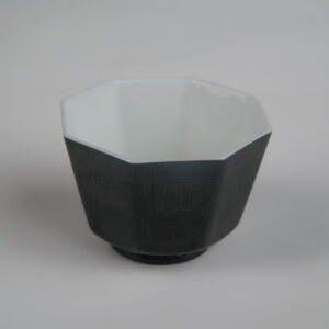 Top-angle front view of the Obsidian Black Octagonal porcelain cup showcasing its geometric octagonal rim, white interior, and solid obsidian black exterior with intricate Shang Dynasty Taotie motif and fine Pa Hua engravings