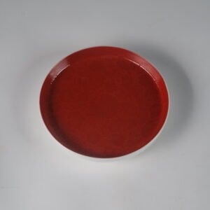 Top down view of round palace red porcelain plate showing carved flower pattern