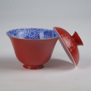 The Palace Red Elegant Charm Gaiwan cup shown without saucer, with its red lid resting on the side to reveal the intricate blue and white floral pattern inside.