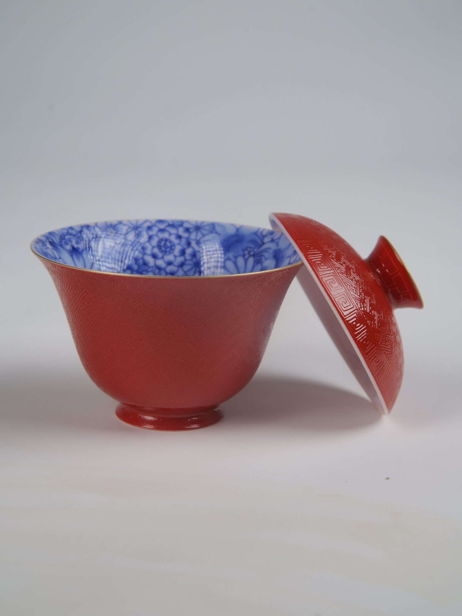 palace-red-elegant-charm-gaiwan-open-lid-no-saucer The Palace Red Elegant Charm Gaiwan cup shown without saucer, with its red lid resting on the side to reveal the intricate blue and white floral pattern inside.
