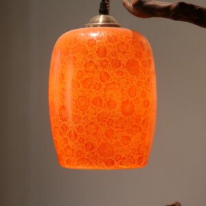 Close up of lit red porcelain lampshade showing intricate floral carved pattern
