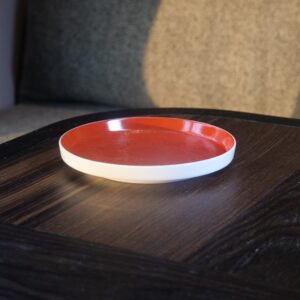 Side view of round red porcelain plate on wooden table