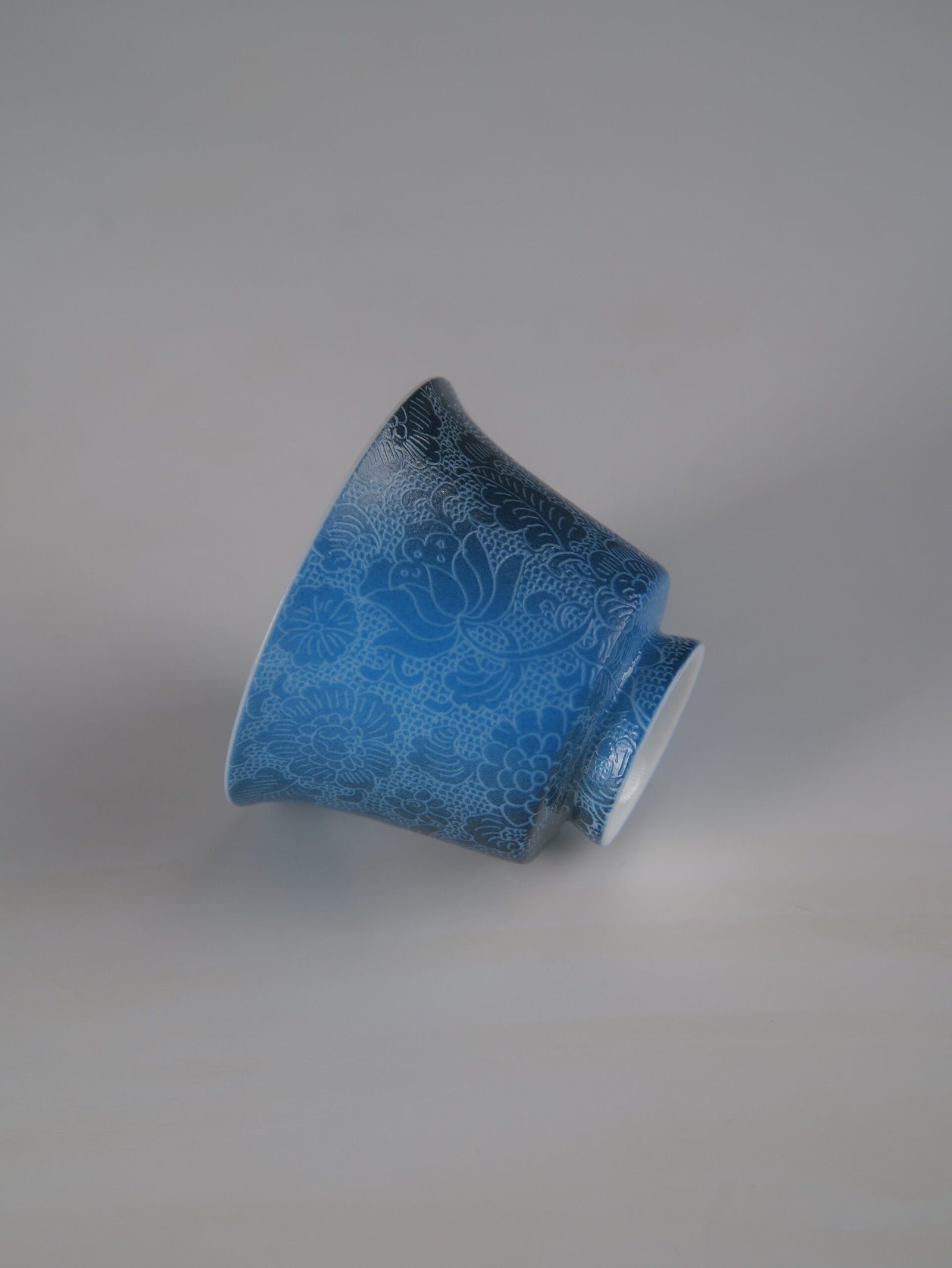 pale-ink-pool-blue-horseshoe-porcelain-cup-inverted-detail An inverted view of the Pale Ink Pool blue porcelain horseshoe cup highlighting its foot rim and detailed floral body engraving