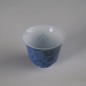 Top-down angle of the Pale Ink Pool blue porcelain horseshoe cup highlighting the inner translucent pattern and outer carved floral texture