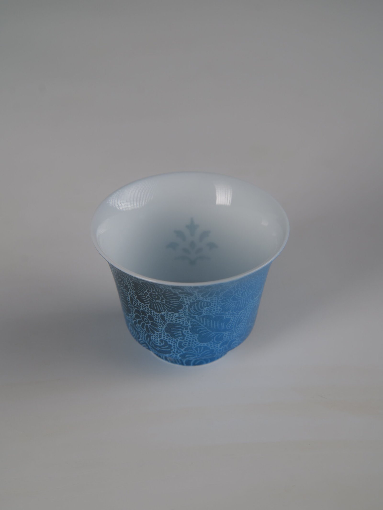 pale-ink-pool-blue-horseshoe-porcelain-cup-top-interior-view Top-down perspective of the Pale Ink Pool blue porcelain horseshoe cup showing the interior subtle watermark and rich outer floral engraving