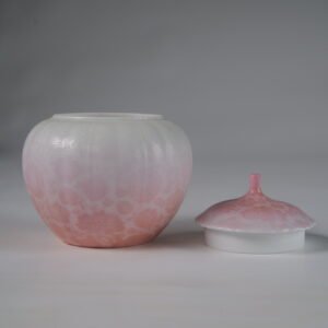 Front view of open peach pink gradient melon jar next to porcelain lid