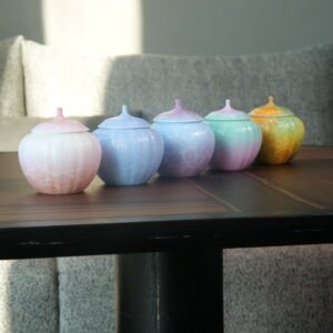 Five colorful gradient porcelain melon jars displayed on a dark wooden tea table