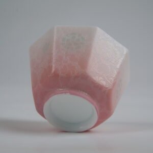 Bottom-angle view of the Peach Pink Gradient Octagonal Glazed Linglong porcelain cup showcasing its white base, geometric octagonal structure, soft peach pink gradient glaze, and delicate carved floral texture with rice-grain Linglong patterns