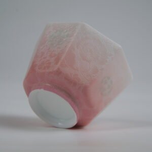 Bottom-up view of the Peach Pink Gradient Octagonal Glazed Linglong porcelain cup showcasing its white base, geometric octagonal facets, soft peach pink gradient glaze, and detailed carved floral patterns