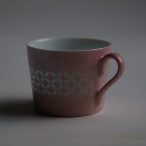 Dark mood side view of pink gradient coffee cup with handle