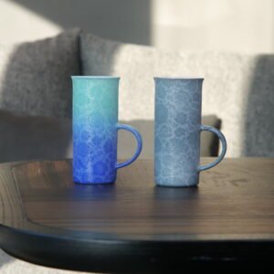Pair of tall porcelain coffee aroma cups in verdant blue and light blue on wooden table