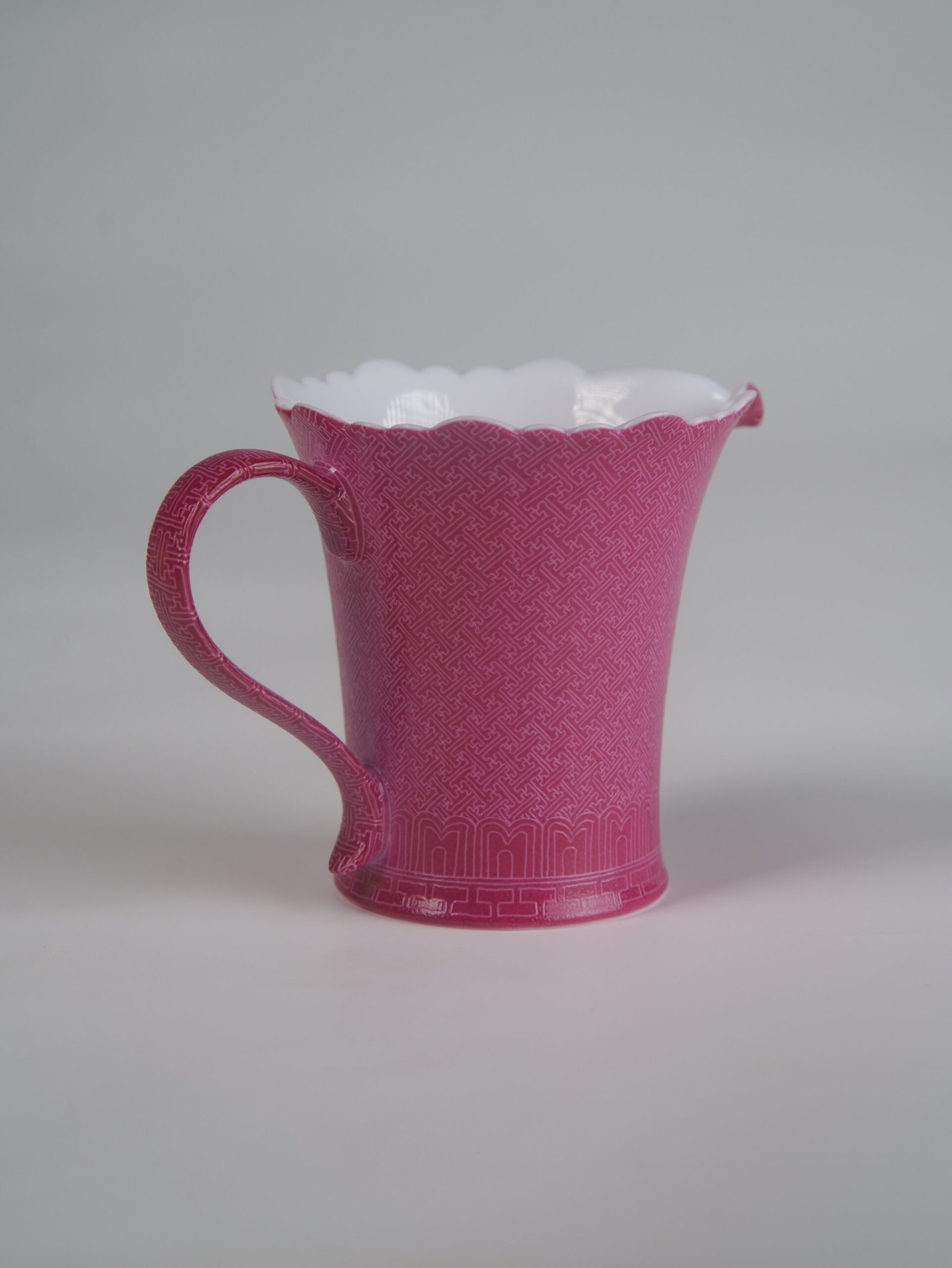 Rouge Red Swastika Pattern Fair Pitcher - Rear Handle View Eye-level rear view facing the handle of a rouge red porcelain flower-rim fair pitcher on white background