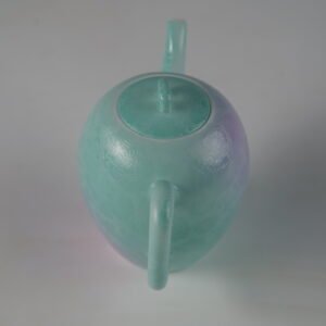 High angle rear perspective view showing the handle and lid knob of a spring glow gradient porcelain teapot